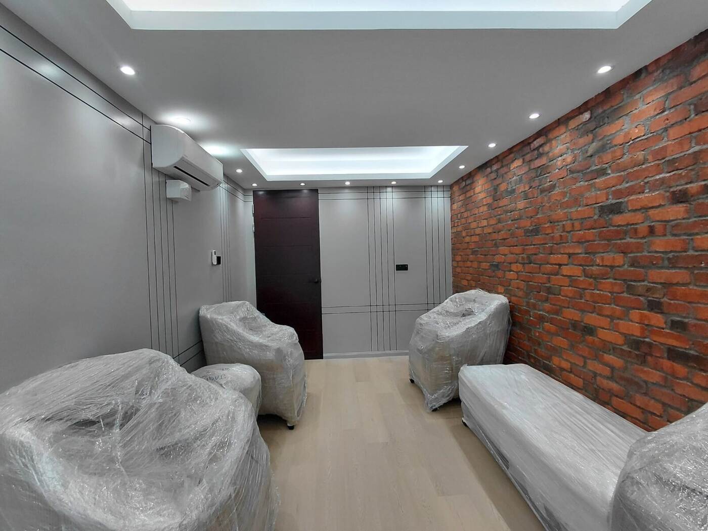Completed corporate office lounge with brick feature wall, timber flooring and recessed ceiling lighting
