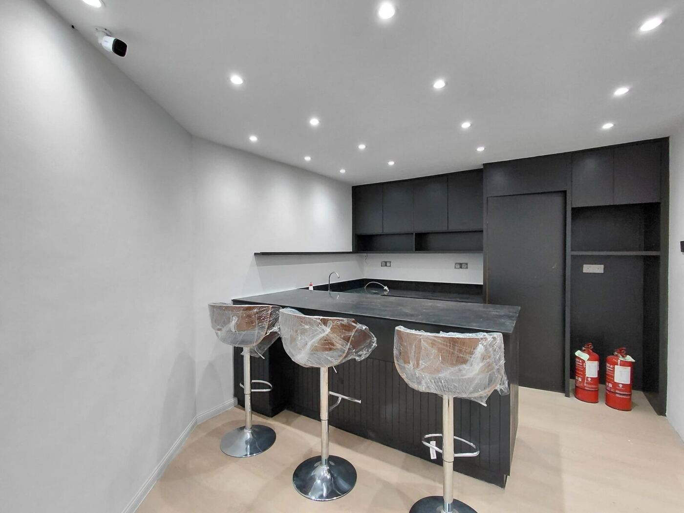 Modern corporate office pantry and breakout counter with dark cabinetry and recessed lighting